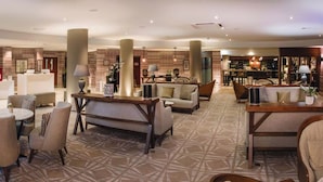 A spacious lobby with multiple seating areas, a reception desk, and a bar area. - Staverton Park Hotel & Golf Club (Daventry)