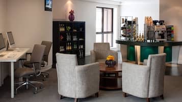 A modern office space with a desk, chairs, a bookshelf, and a coffee station.