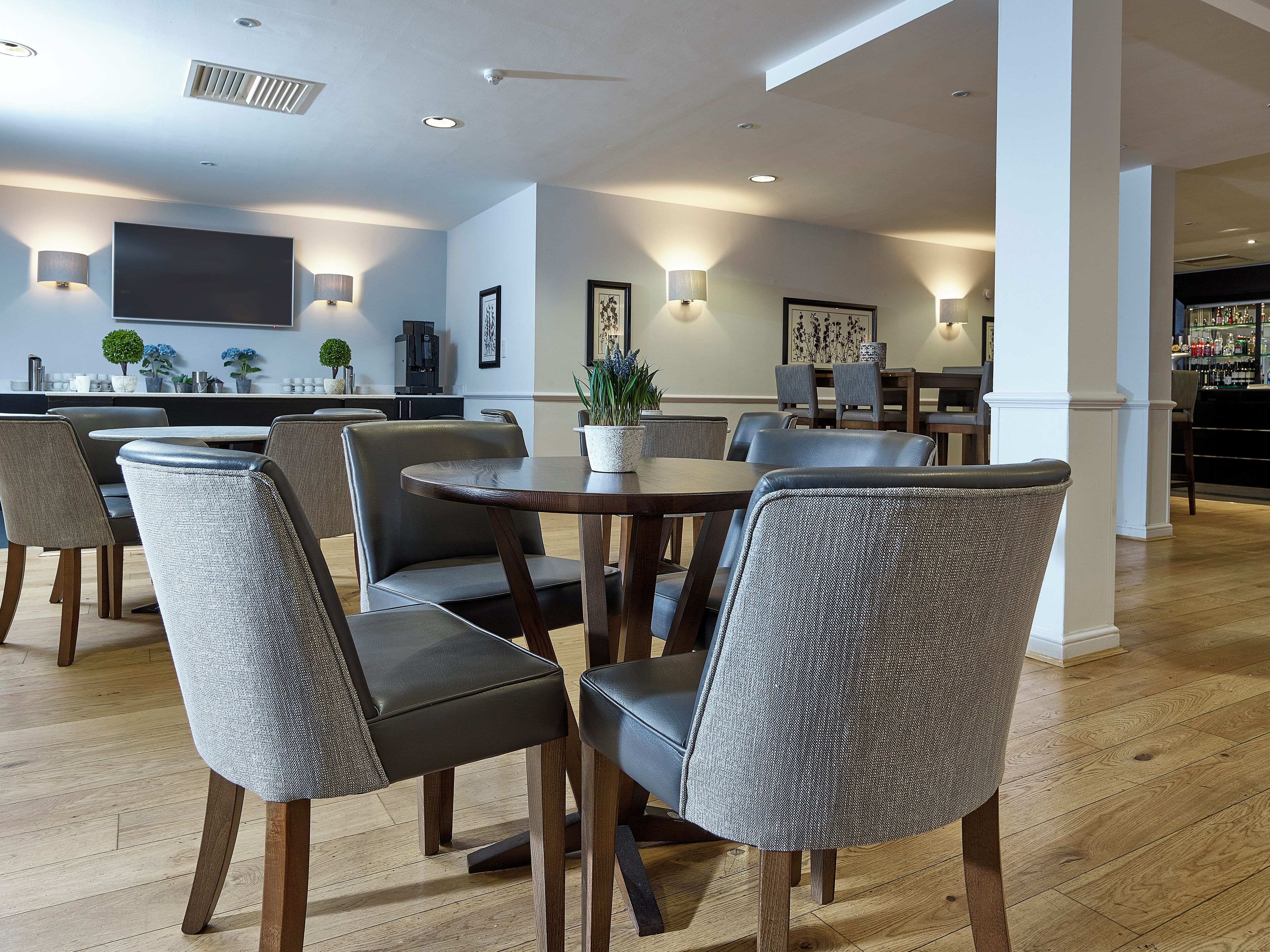 Un comedor moderno con una mesa redonda y seis sillas, una cocina al fondo y una barra a la derecha.