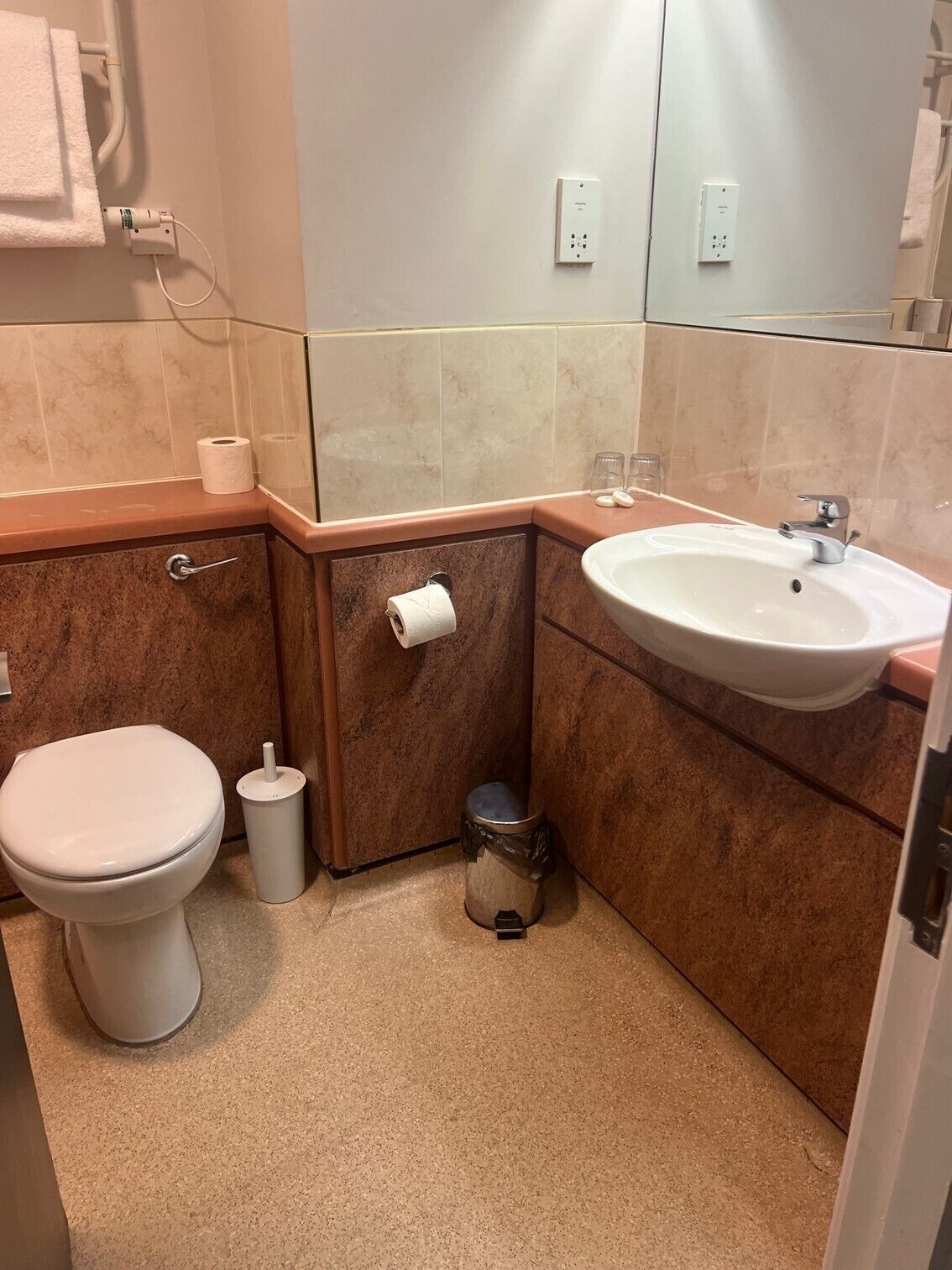 A bathroom with a toilet, sink, and trash can.
