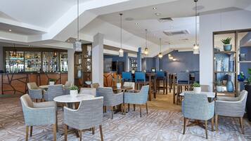 A modern hotel lobby with a bar area, seating arrangements, and a patterned carpet.