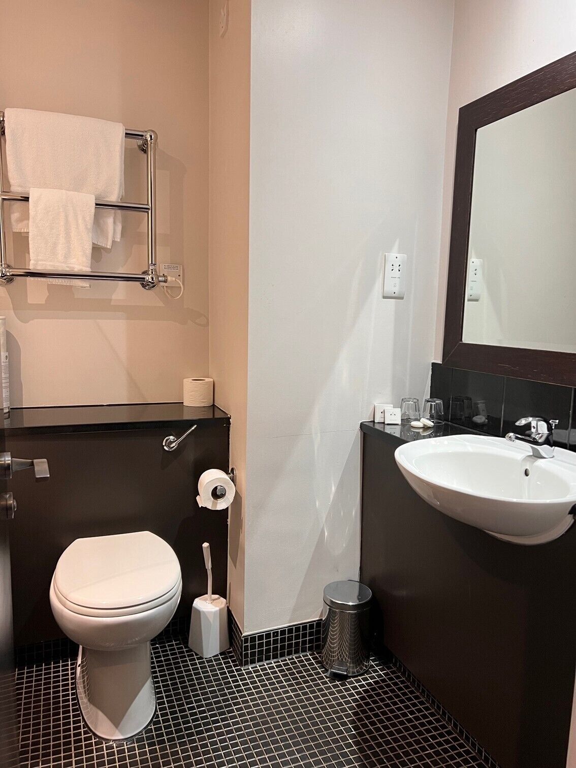 Un baño moderno con inodoro, lavamanos y toallero.