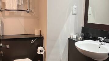 Un baño moderno con inodoro, lavamanos y toallero.