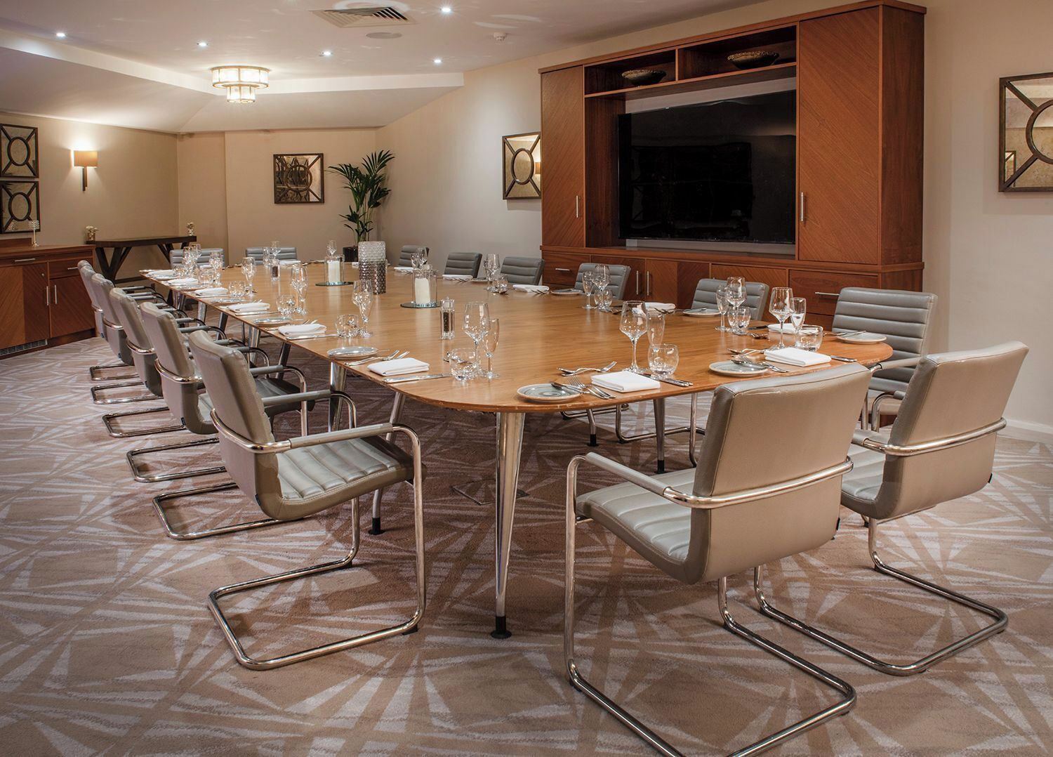 A conference room with a long table, chairs, and a large cabinet.