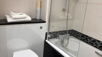 A modern bathroom with a toilet, a glass-enclosed shower, and a bathtub.