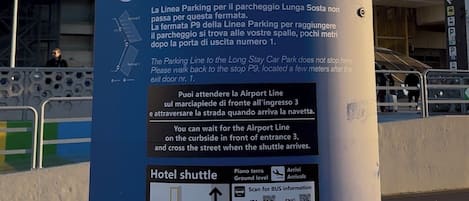 Un panneau cylindrique bleu indiquant la ligne de liaison avec l’aéroport, placé dans l’aéroport, et signalant le point de prise en charge de l’hôtel Hilton Garden Inn.