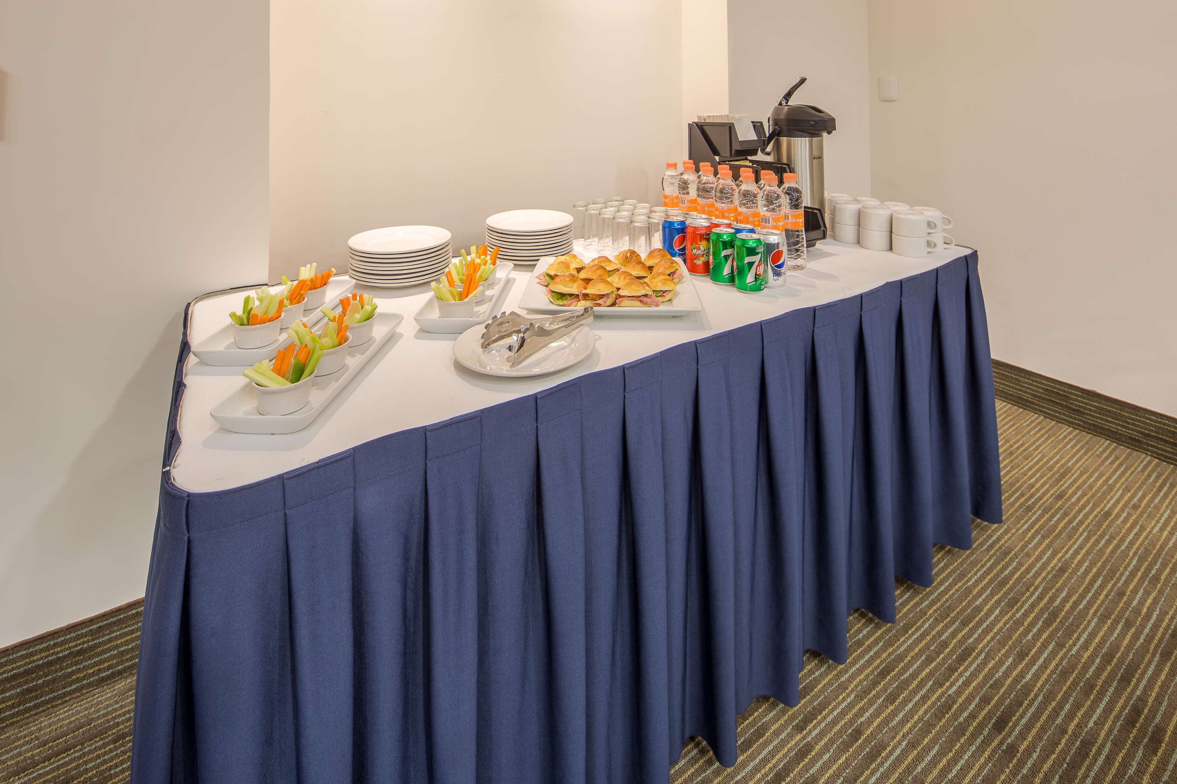 Una mesa de buffet con diversos alimentos, platos y bebidas.