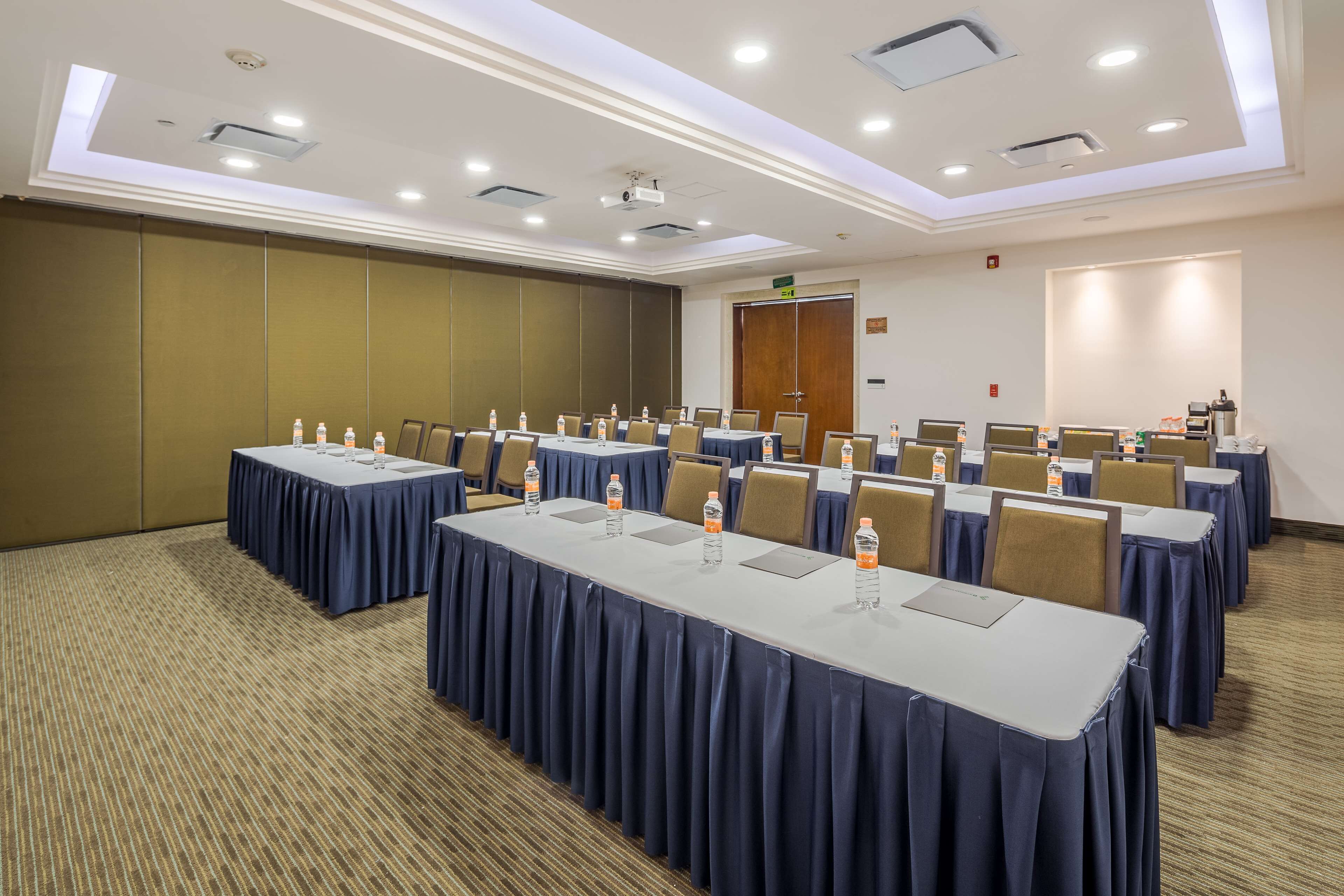 A conference room with long tables, chairs, and water bottles.