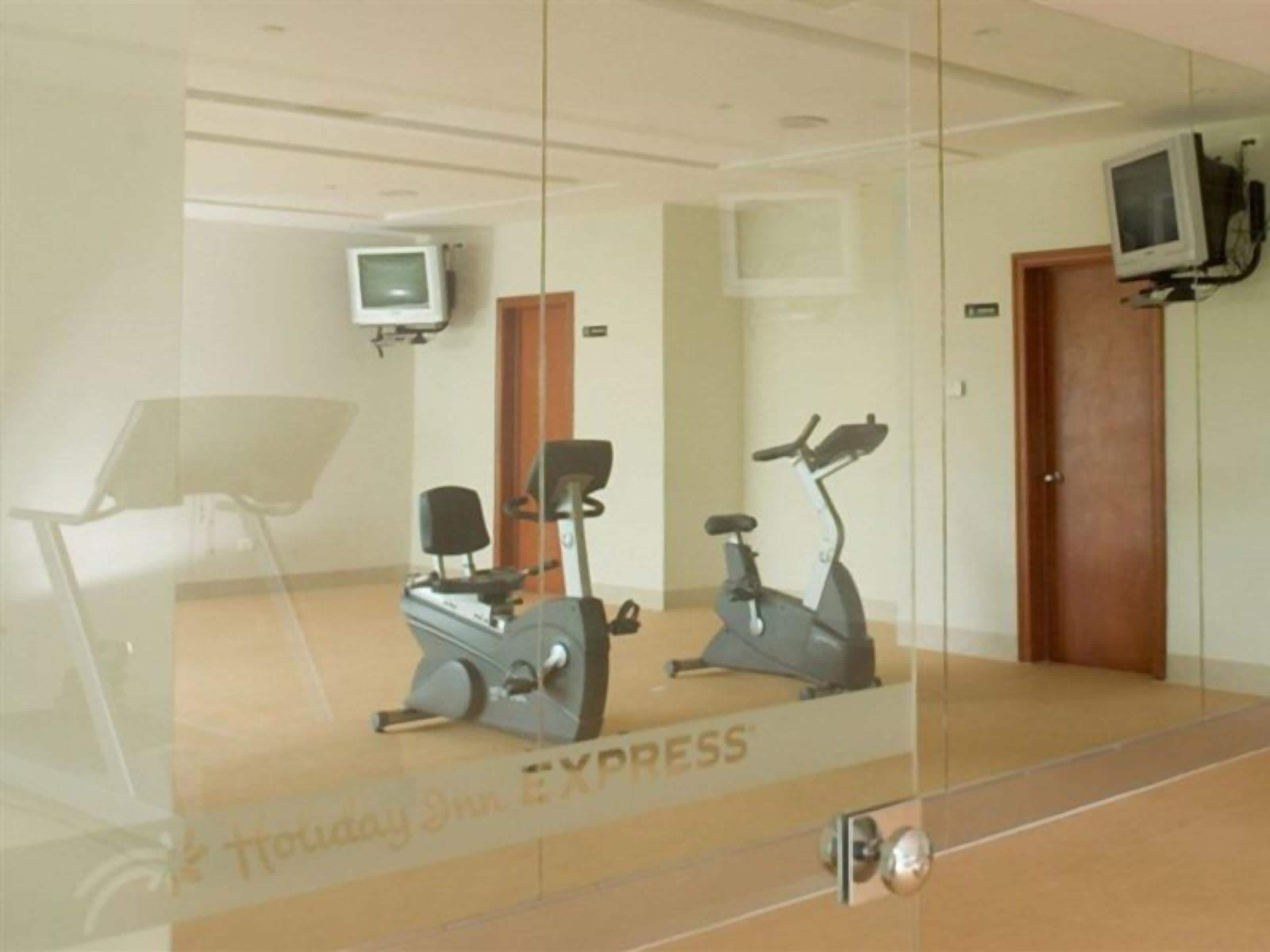 A mirrored room with exercise equipment, a television, and a door.