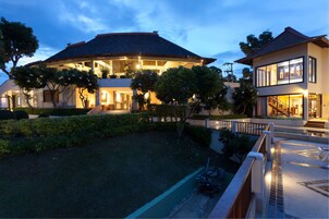 A modern two-story house with a large open-plan living area, a balcony, and a well-maintained garden.