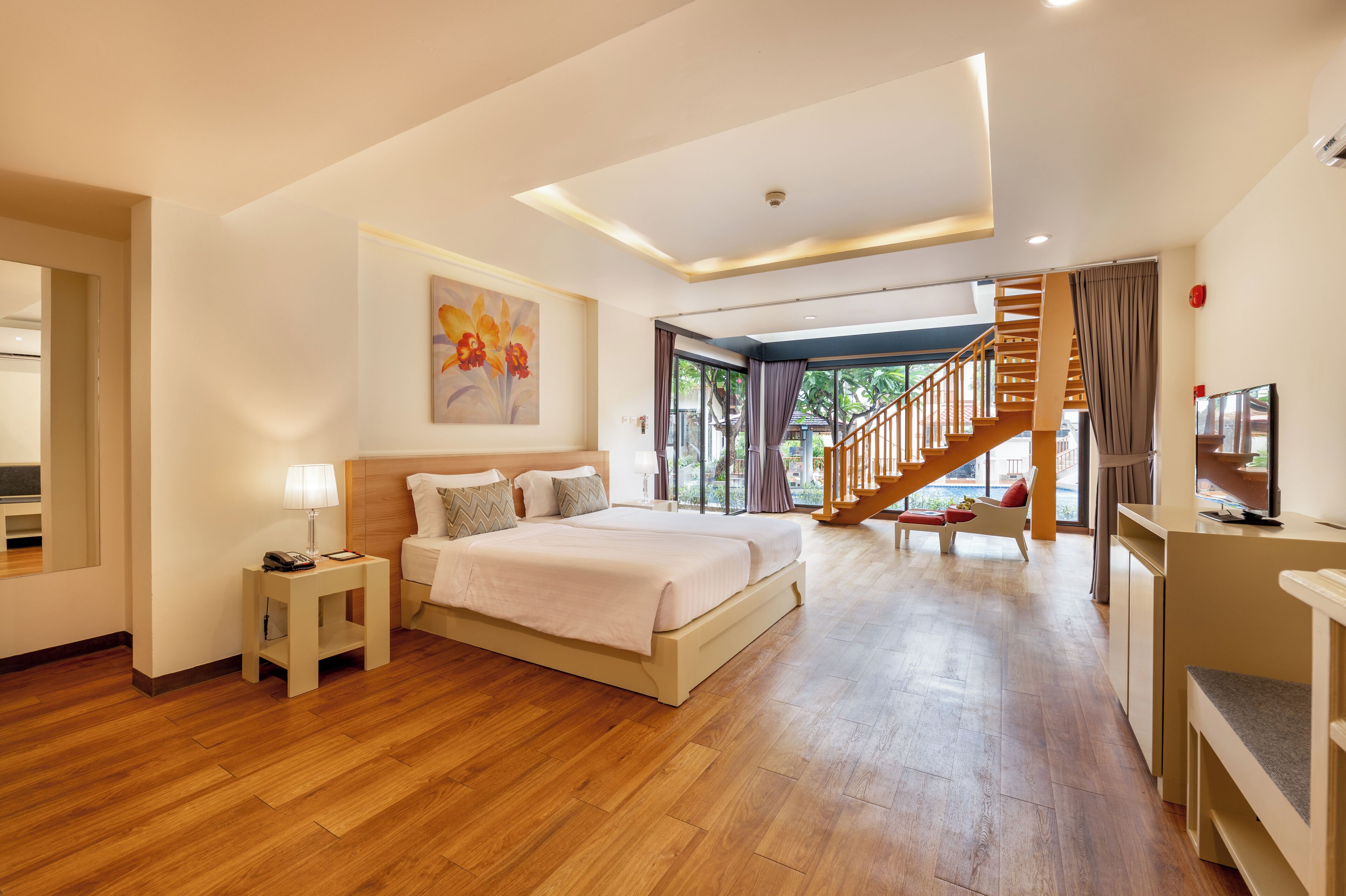 A modern hotel room with a large bed, a small bedside table, a TV, and a staircase leading to an outdoor area.