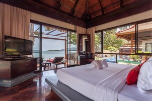 Habitación de hotel con una cama grande, televisión, escritorio y vista al mar.