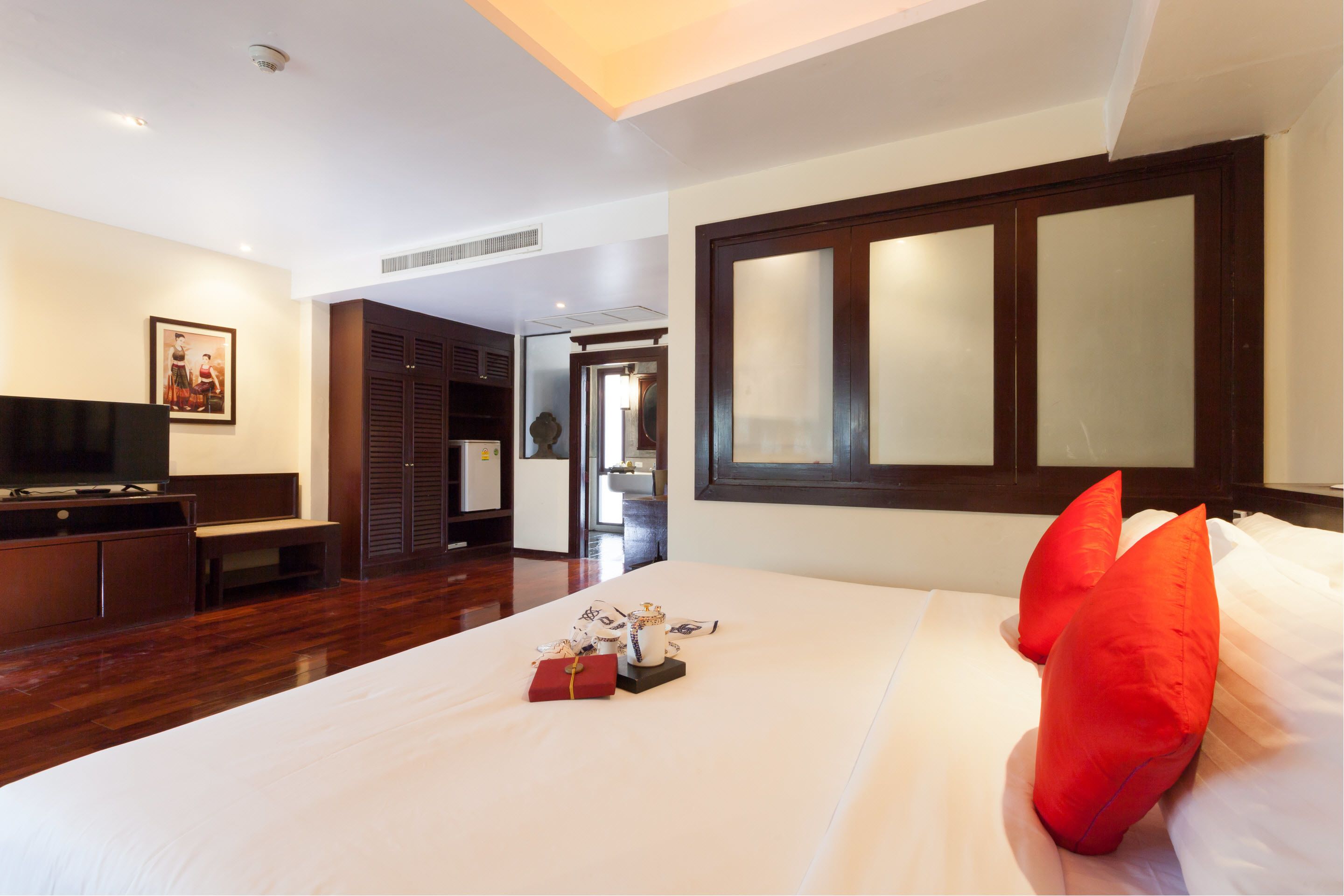 Una habitación de hotel con cama, televisión, armario y un amplio ventanal.