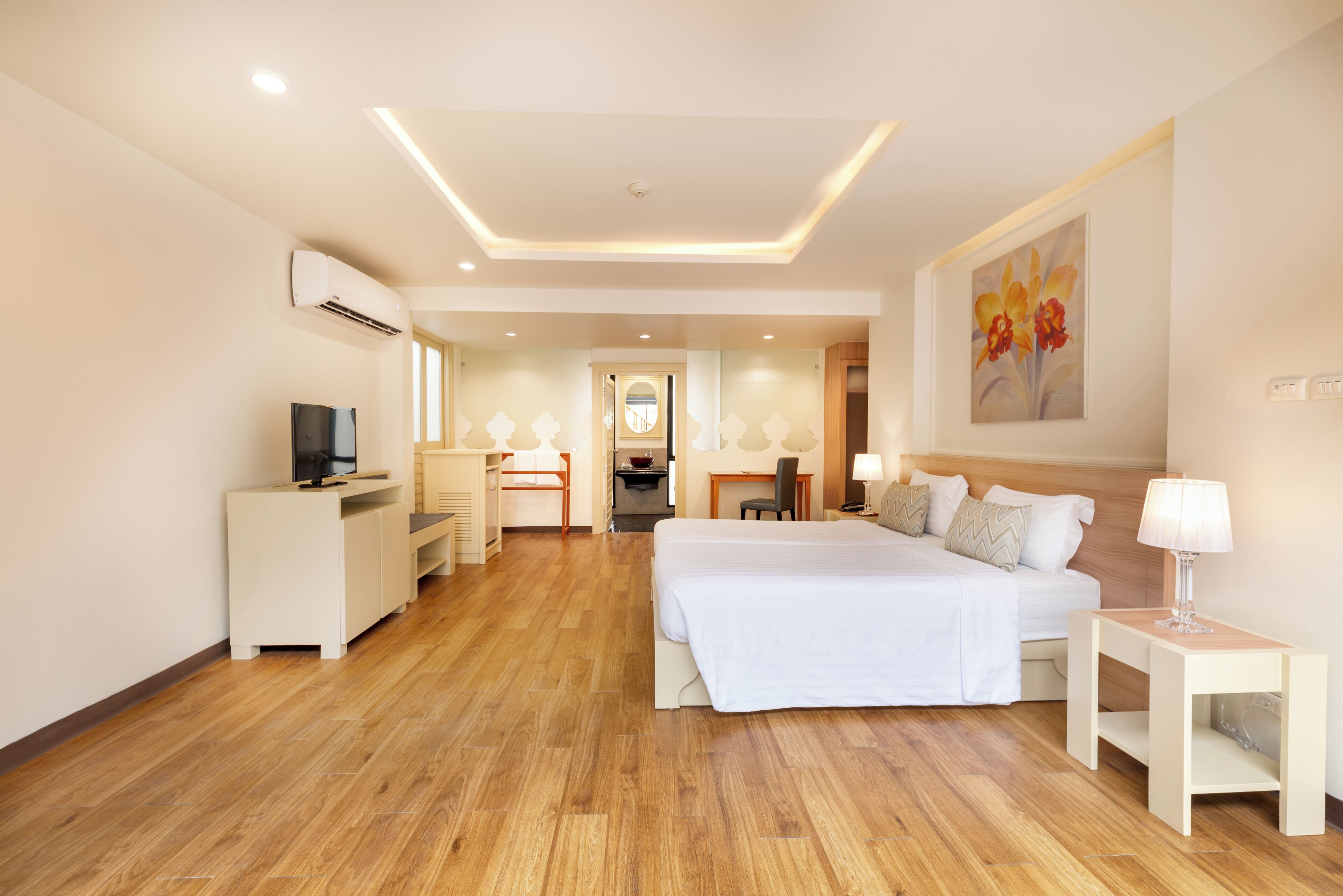 A modern hotel room with a large bed, a desk, a chair, and a TV.