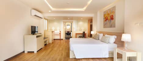 A modern hotel room with a large bed, a desk, a chair, and a TV.