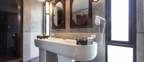 A modern bathroom with a large sink, two mirrors, and a hairdryer on the wall.