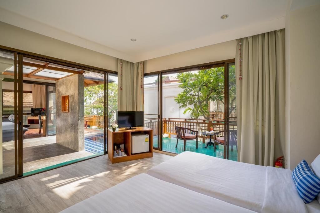 A modern hotel room with a large bed, a TV, and a balcony with a pool.