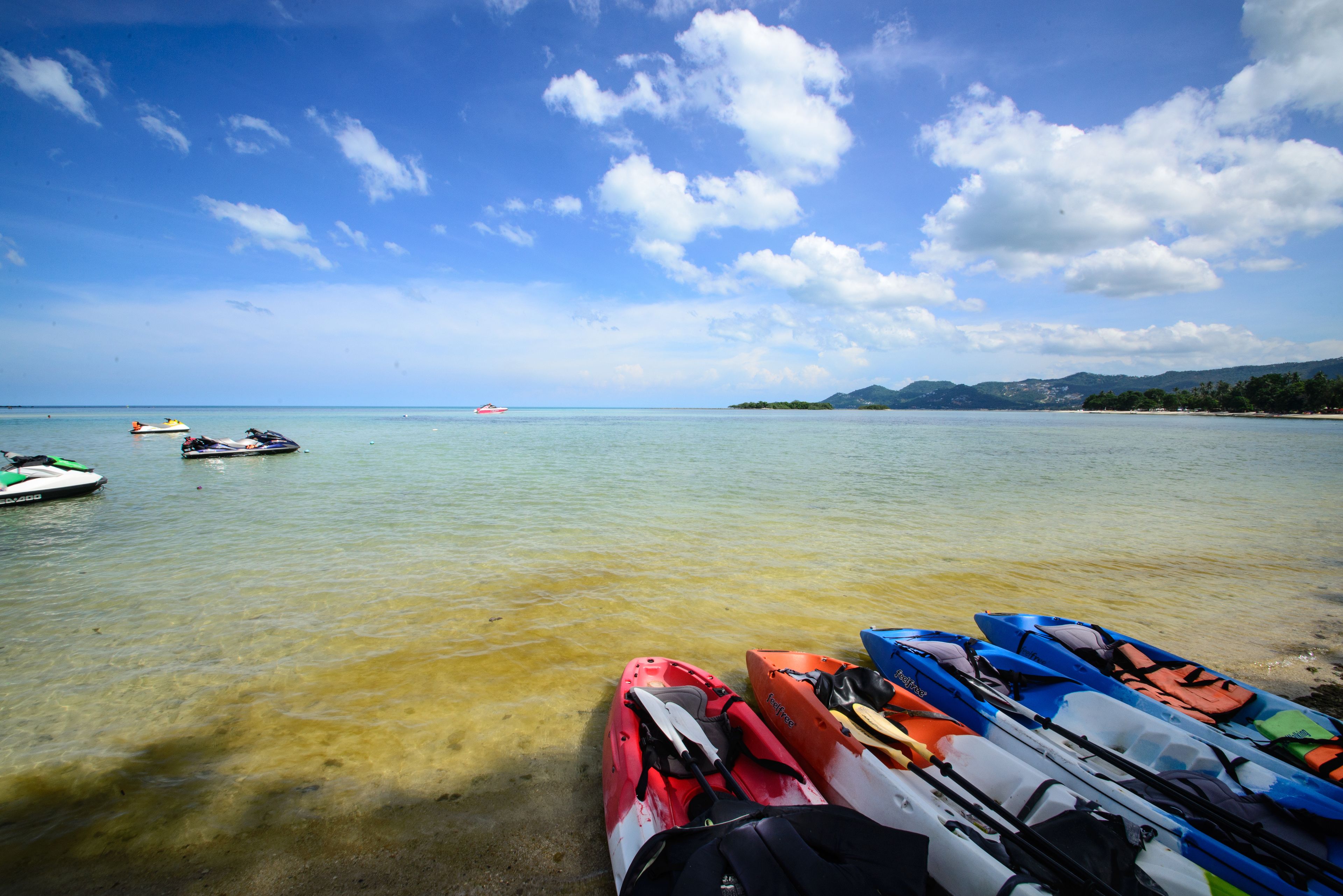 A calm body of water with kayaks and a small boat docked near the shore.