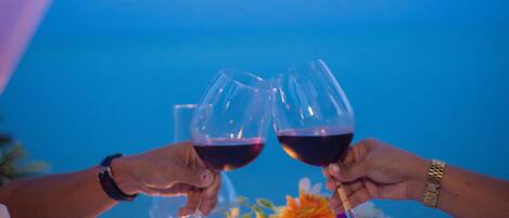 Una mesa con una vela, un jarrón de flores y dos copas de vino.