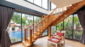 A spacious room with a wooden staircase leading to a balcony overlooking a swimming pool. - The Briza Beach Resort, Samui (Koh Samui)