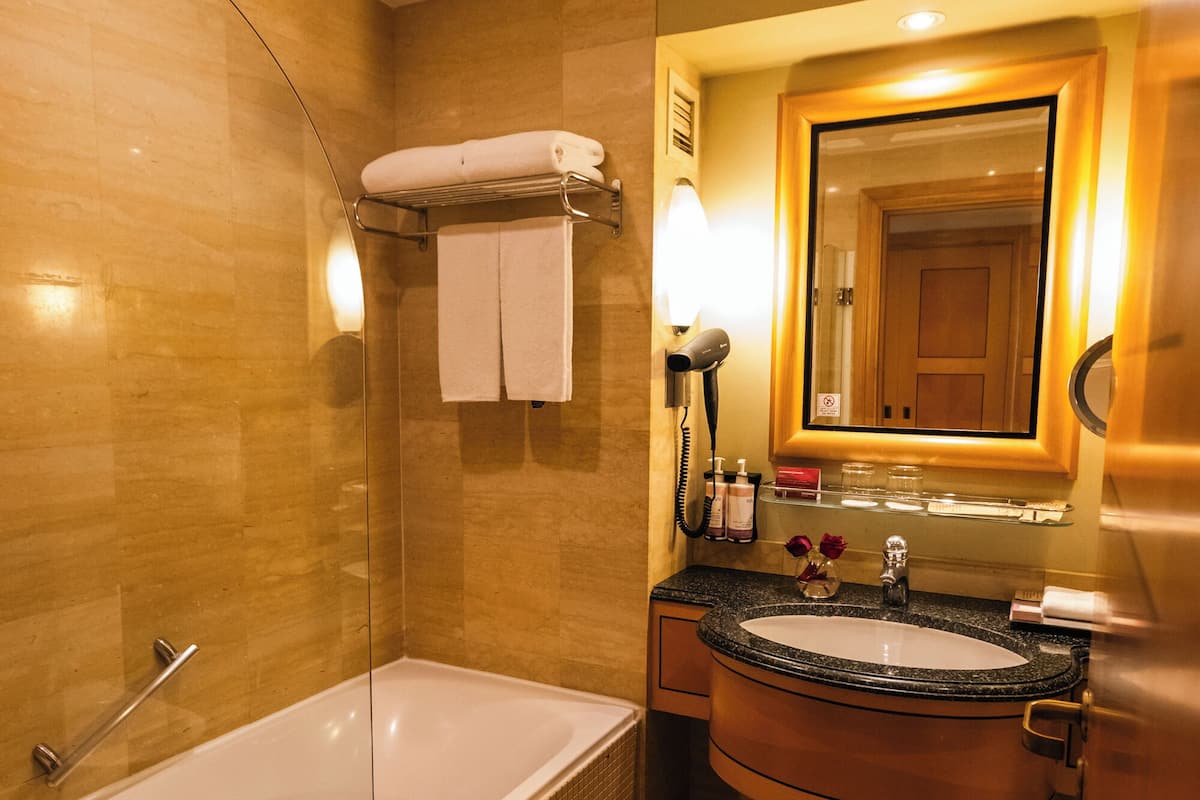 Ein Badezimmer mit einer Badewanne, einem Waschbecken, einem Spiegel und einem Handtuchhalter.