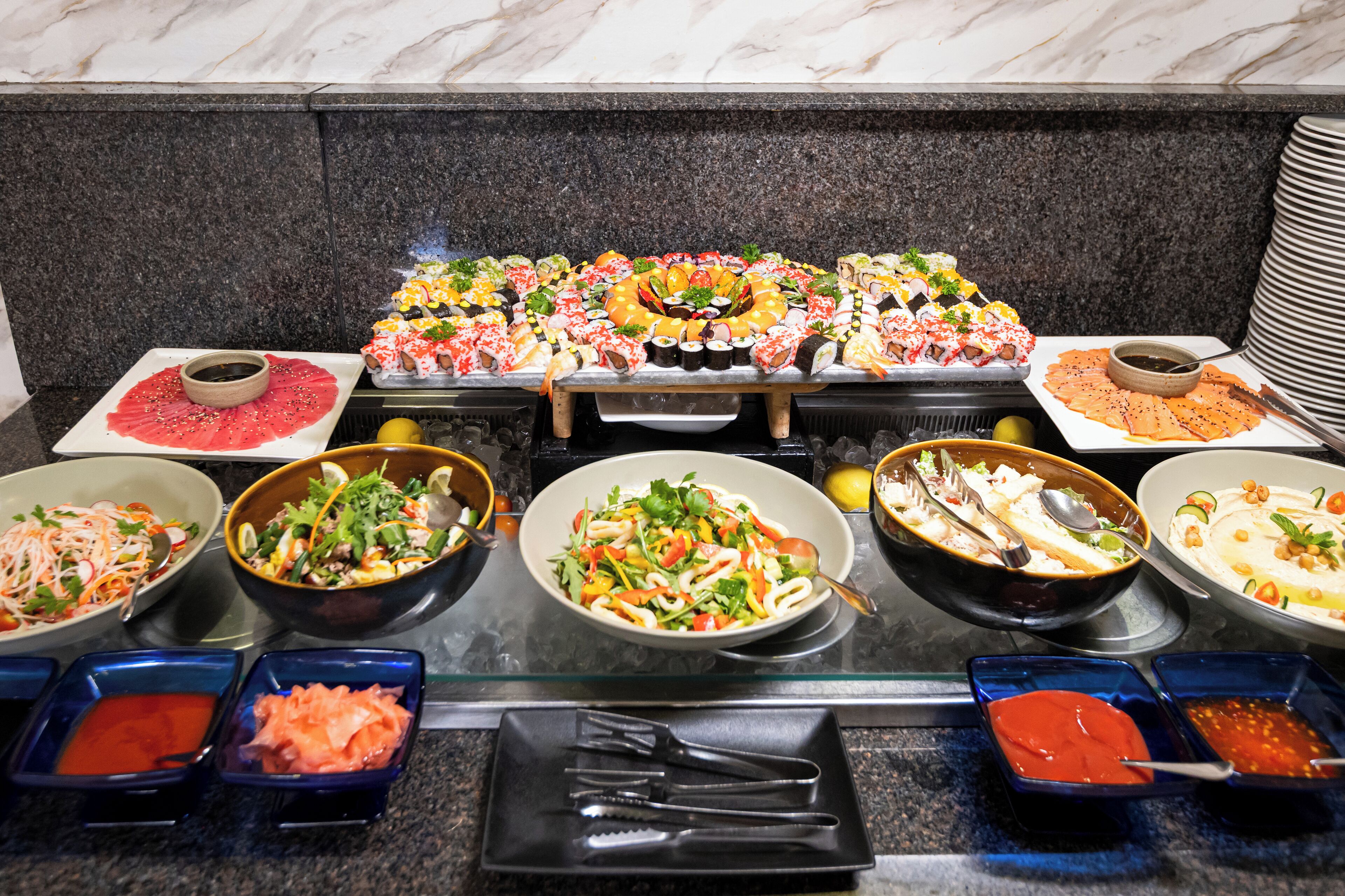 A buffet with various dishes, including sushi, salads, and dips.