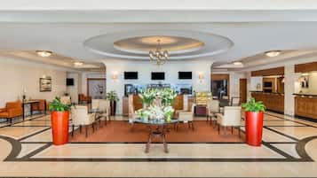 A hotel lobby with a reception desk, seating area, and a bar.