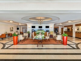 Un vestíbulo de hotel con recepción, zona de estar y bar.