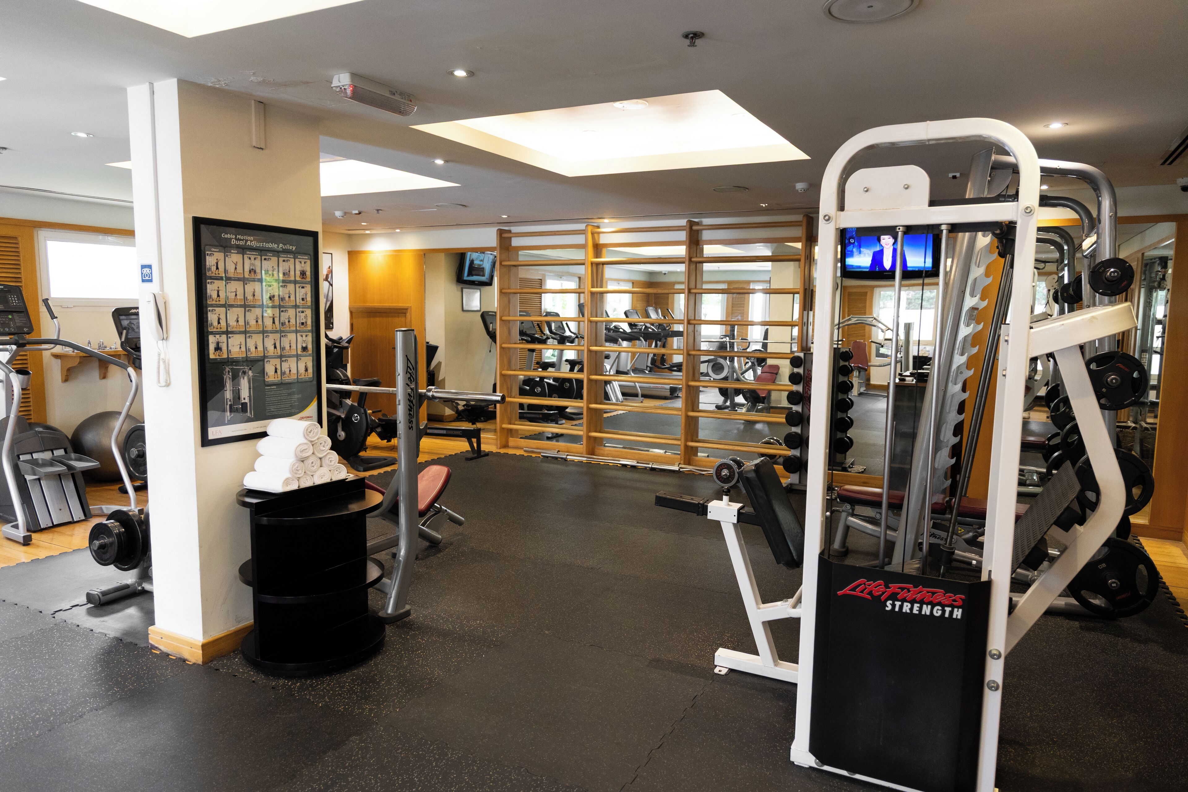 Une salle de sport équipée de tapis de course, d’appareils de musculation et d’un écran de télévision.