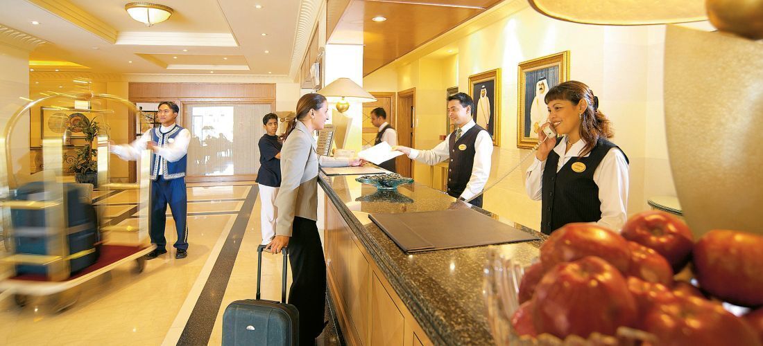 A hotel reception area with a counter, a waiting area, and a view of the lobby.