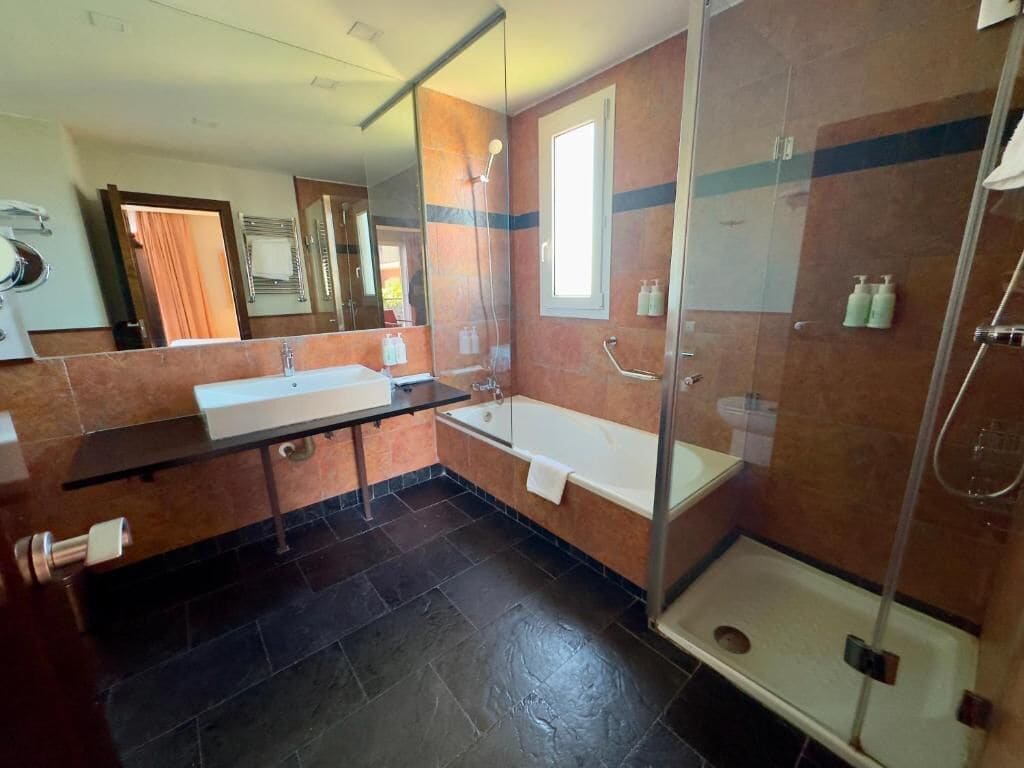 Un baño moderno con cabina de ducha de vidrio, bañera y tocador con espejo.