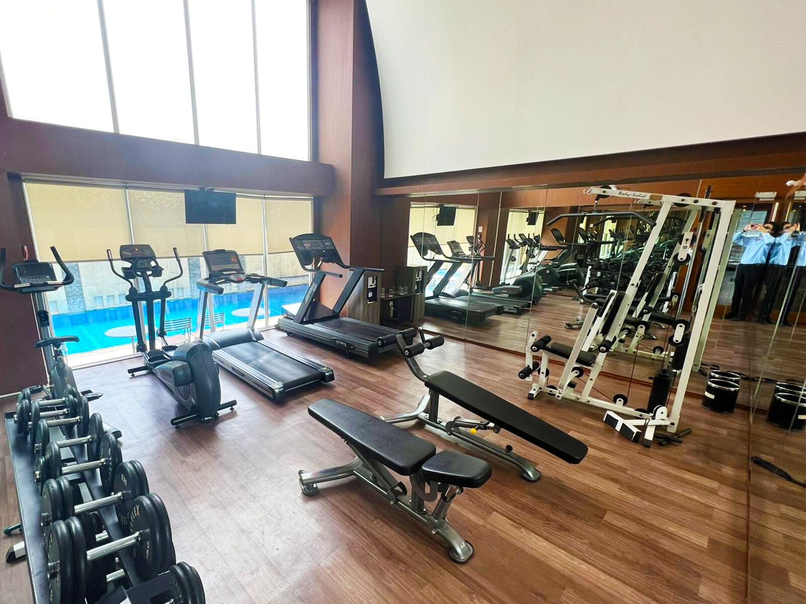 Une salle de sport équipée de tapis de course, de vélos elliptiques, de poids libres et d’un banc de musculation.