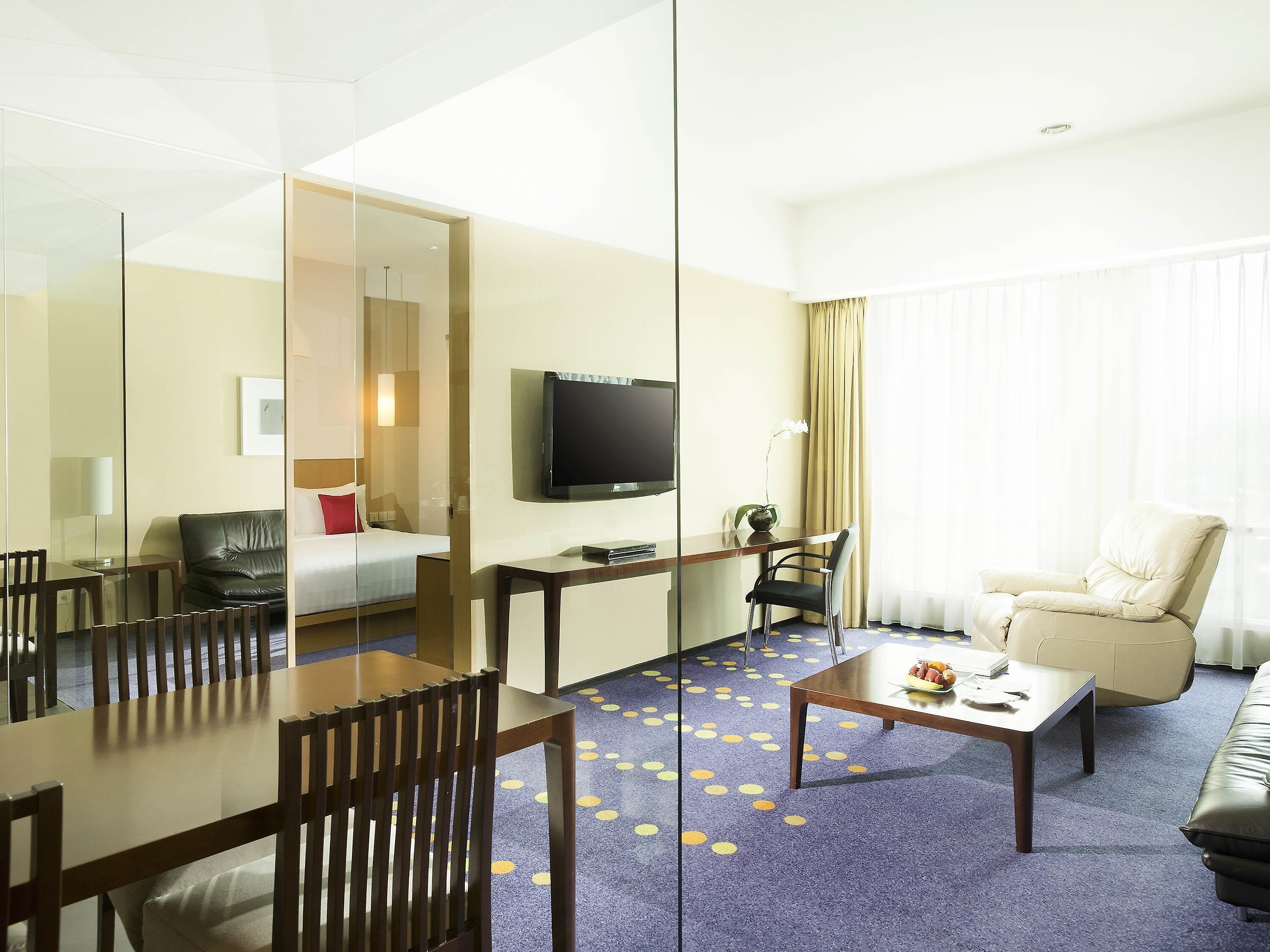 A hotel room with a bed, a TV, a desk, a chair, and a sofa.