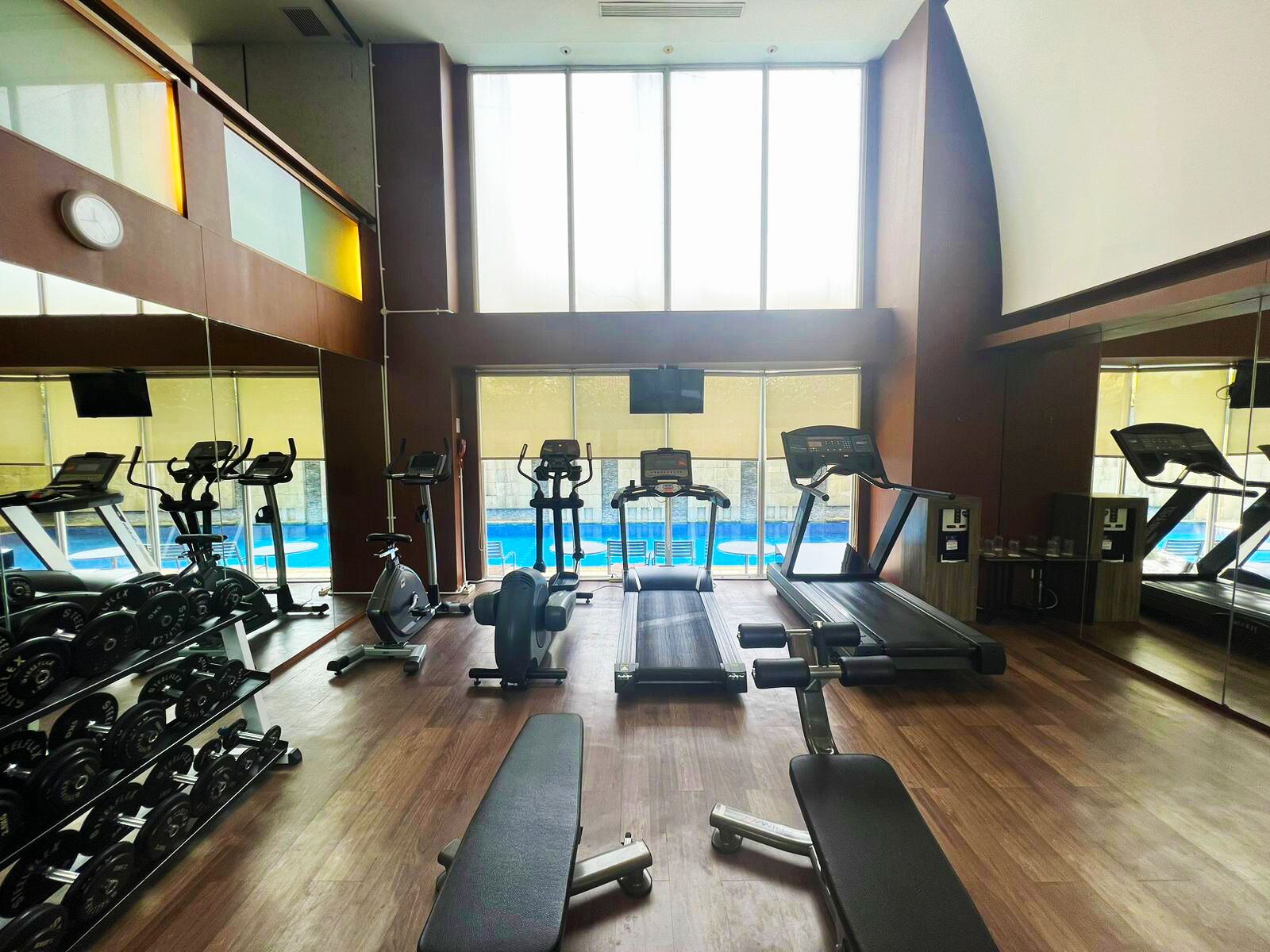 A gym with treadmills, elliptical machines, and weight racks.