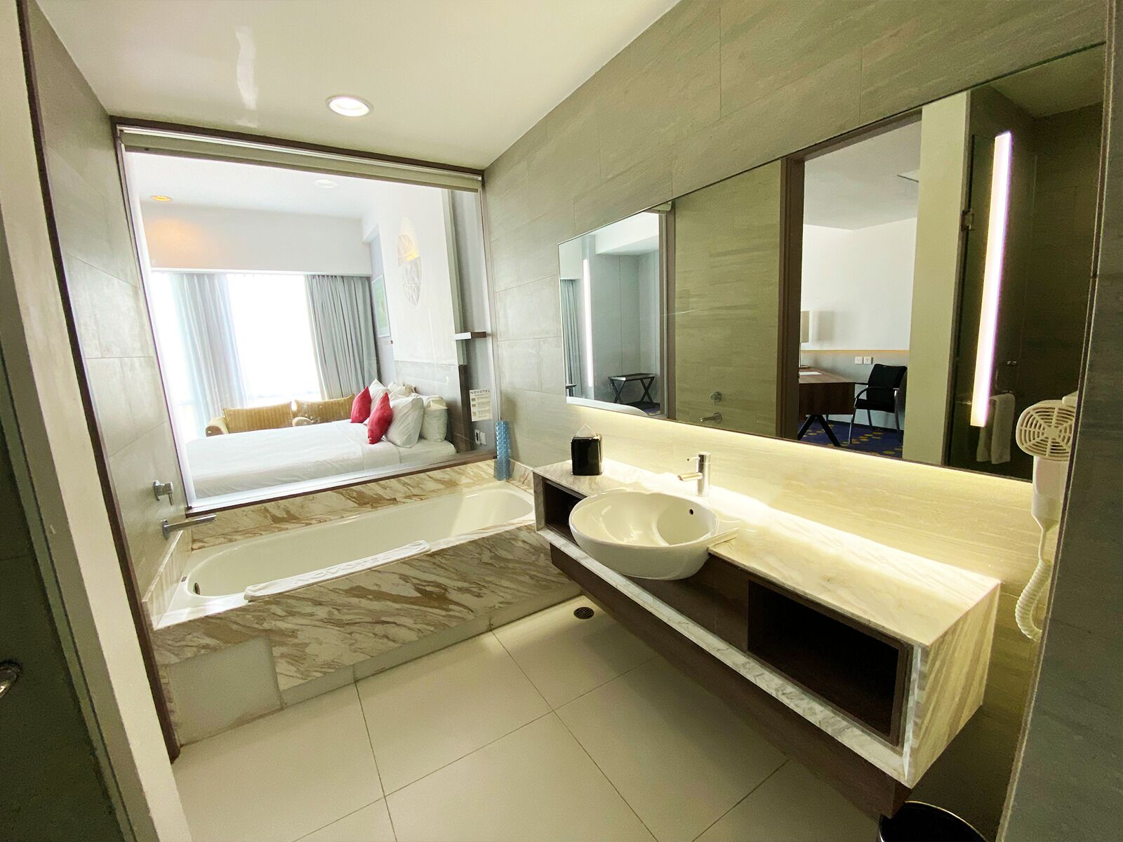 A modern bathroom with a large bathtub, a sink, and a mirror.