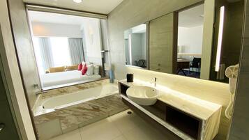 A modern bathroom with a large bathtub, a sink, and a mirror.