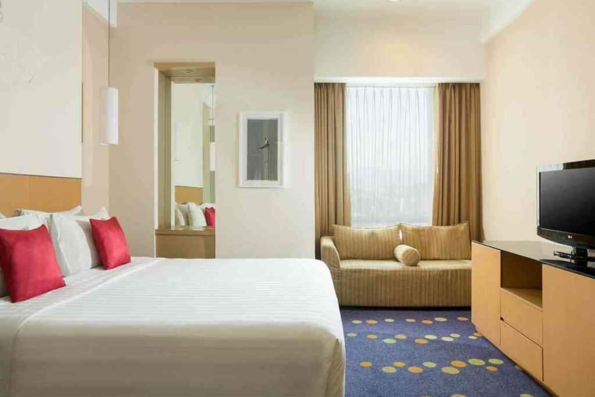 Ein Hotelzimmer mit Bett, einer Couch, einem Fernseher und einer Badezimmertür.