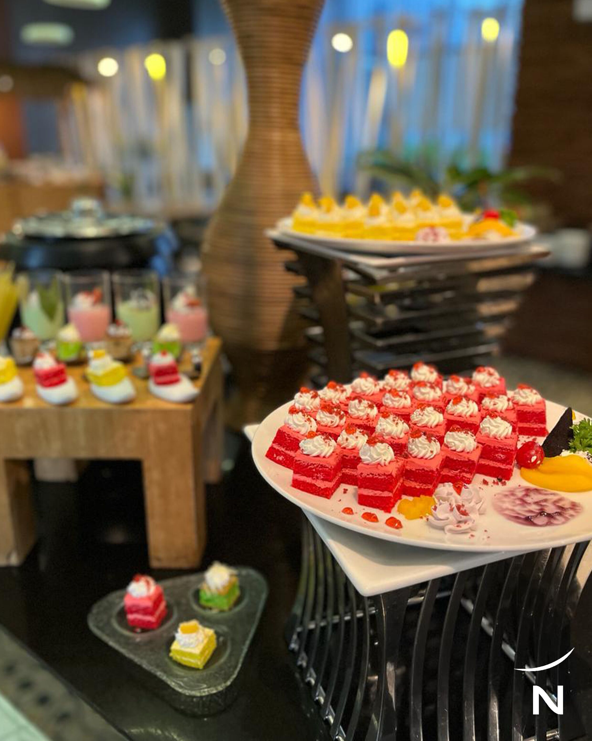 Un bufé de postres con dulces de diversos colores y una decoración central.