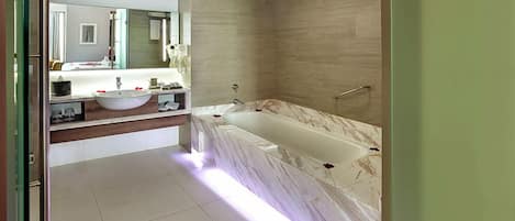 Un baño moderno con una bañera de mármol, un espejo grande y un tocador con lavamanos.