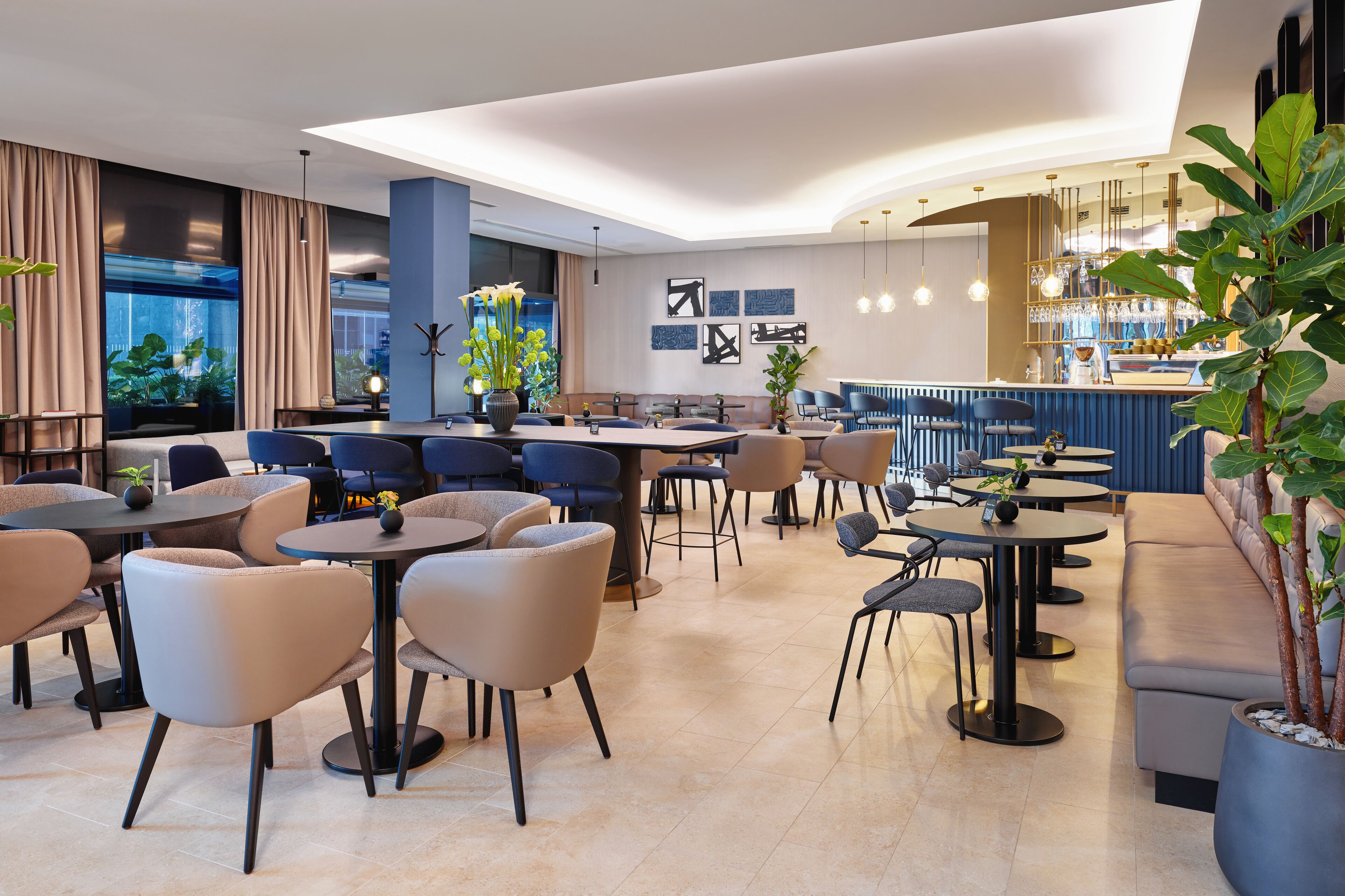 A modern lounge area with multiple seating options, including sofas and tables, and a bar area with a counter and seating.