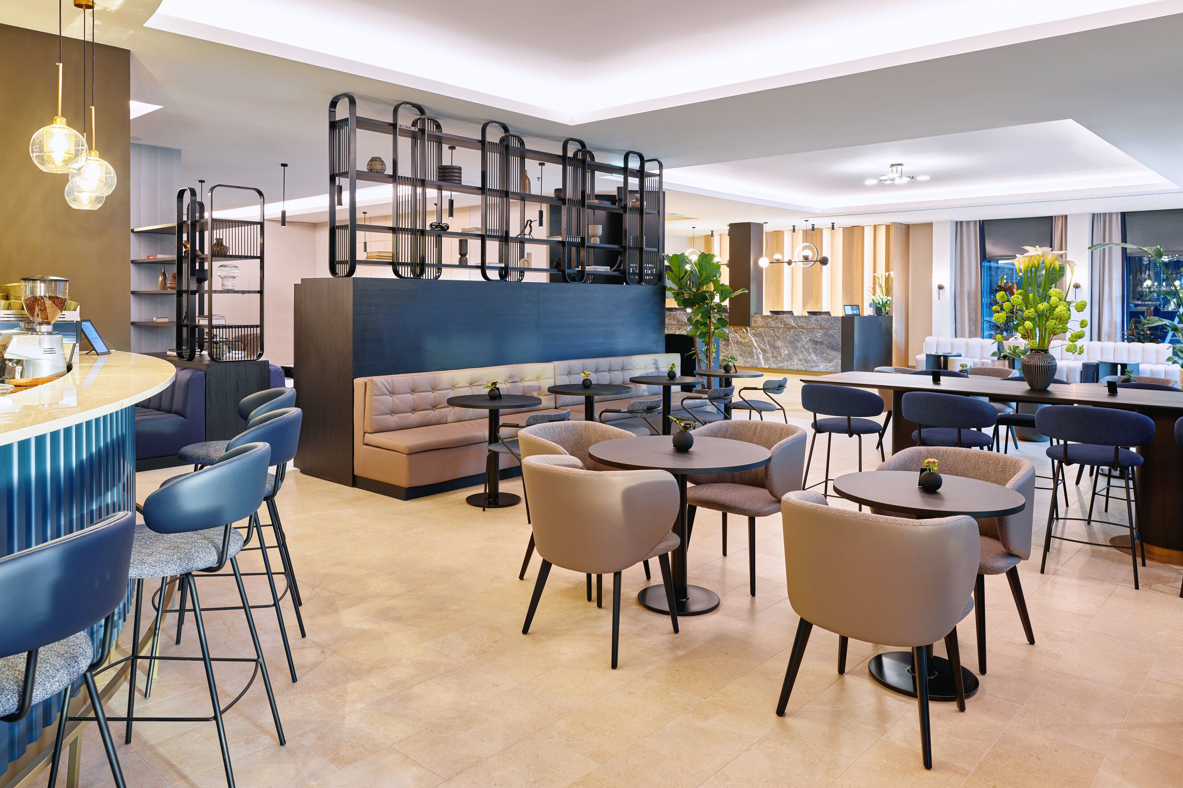A modern lounge area with a sofa, round tables, and bar seating.