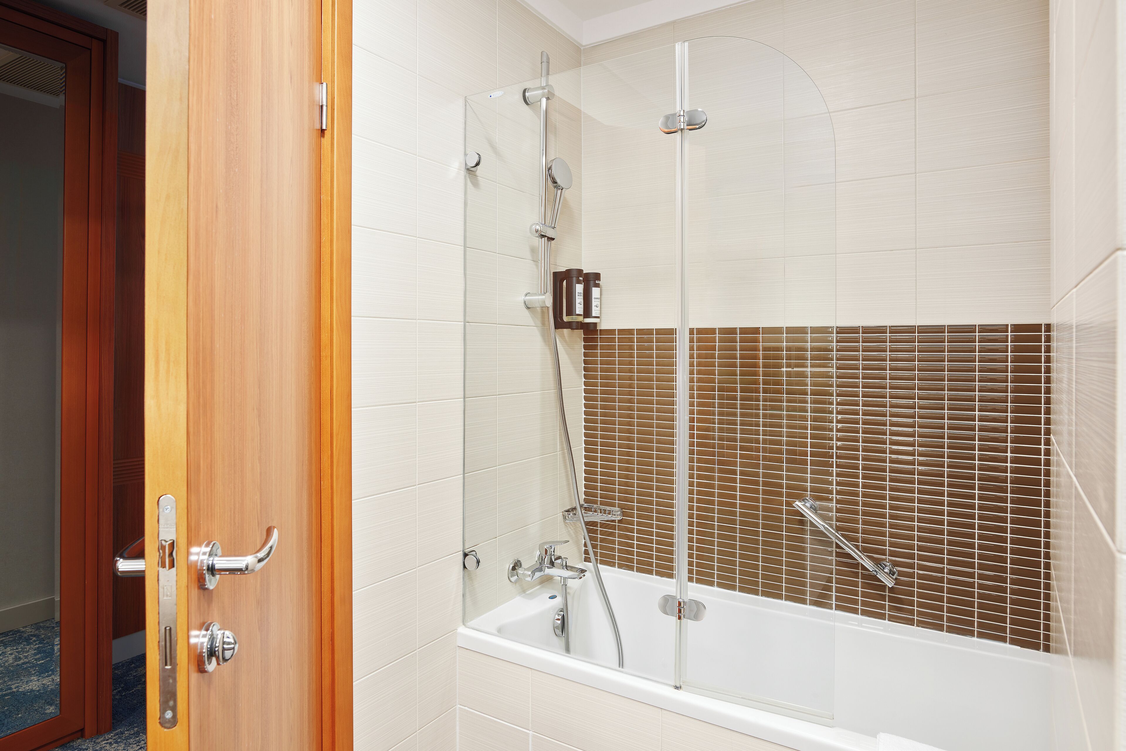 Un baño con bañera, ducha y puerta de madera.