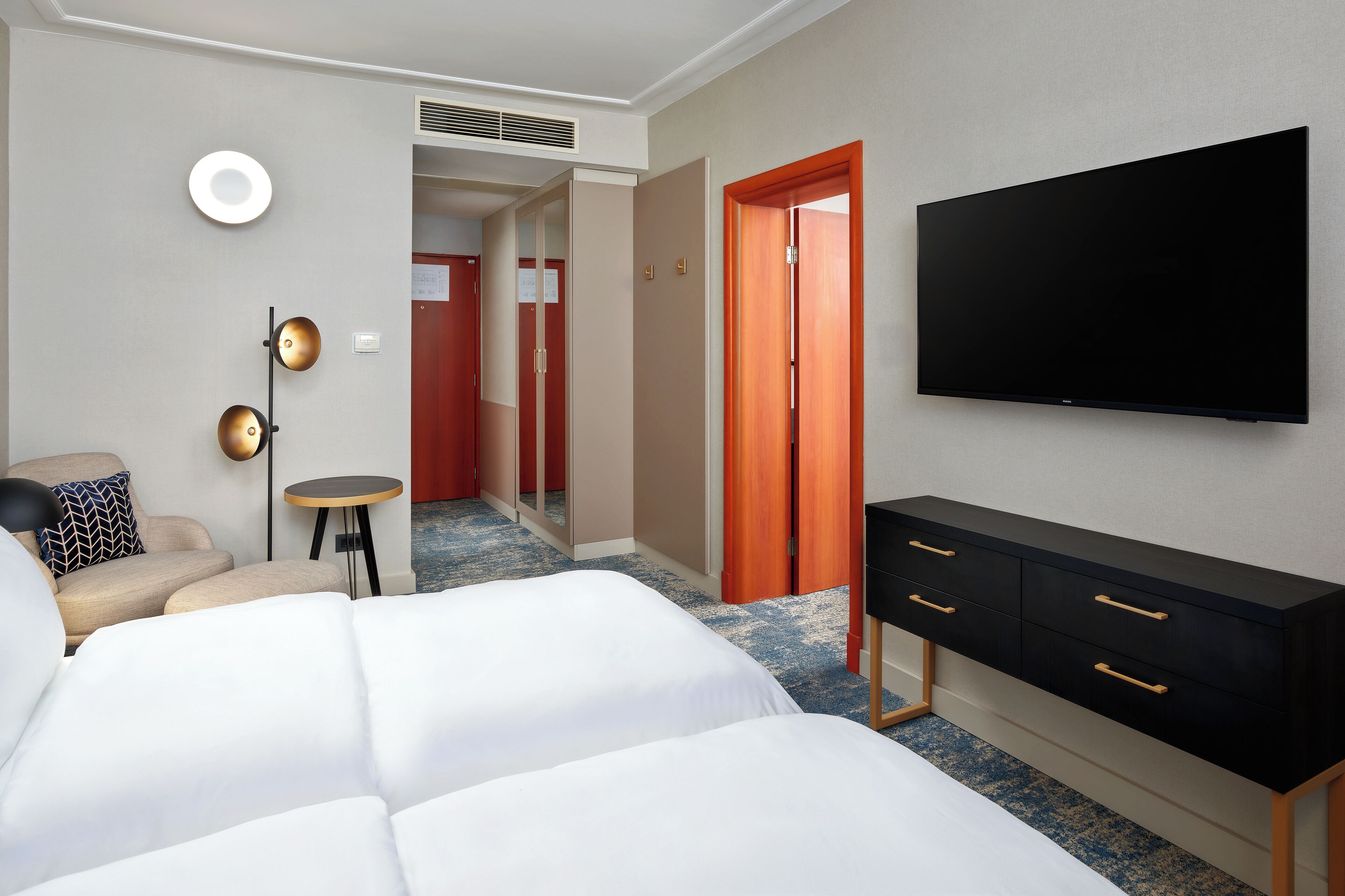 Una habitación de hotel con una cama, televisión, escritorio y una silla.