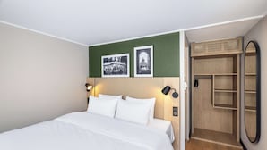 A neatly made bed with white linens, a green accent wall, and two black-framed wall sconces. - Campanile NATURE - Cergy Saint Christophe (Osny)