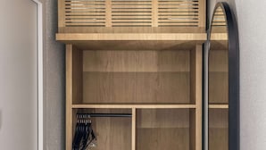 A walk-in closet with wooden shelving, a hanging rod, and a mirrored closet door. - Campanile NATURE - Cergy Saint Christophe (Osny)