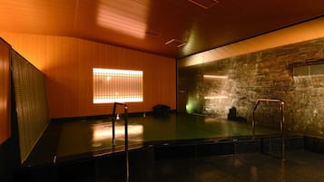 Ein moderner Innenpoolbereich mit Holzverkleidung, einer Glaswand und einer Metallleiter.