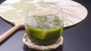 A glass of green beverage on a woven coaster.