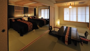 A traditional Japanese-style room with tatami flooring, a low table with a red and black patterned table runner, and a bed with black bedding and red accents. - Matsui Honkan (Kyoto)
