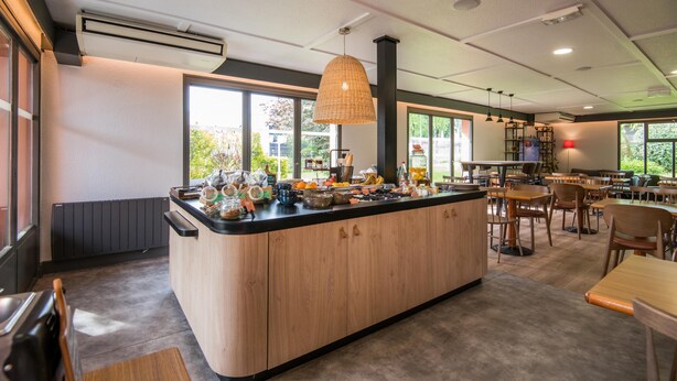 Una cocina moderna con una isla central, ventanas amplias y una zona de comedor con mobiliario de madera.