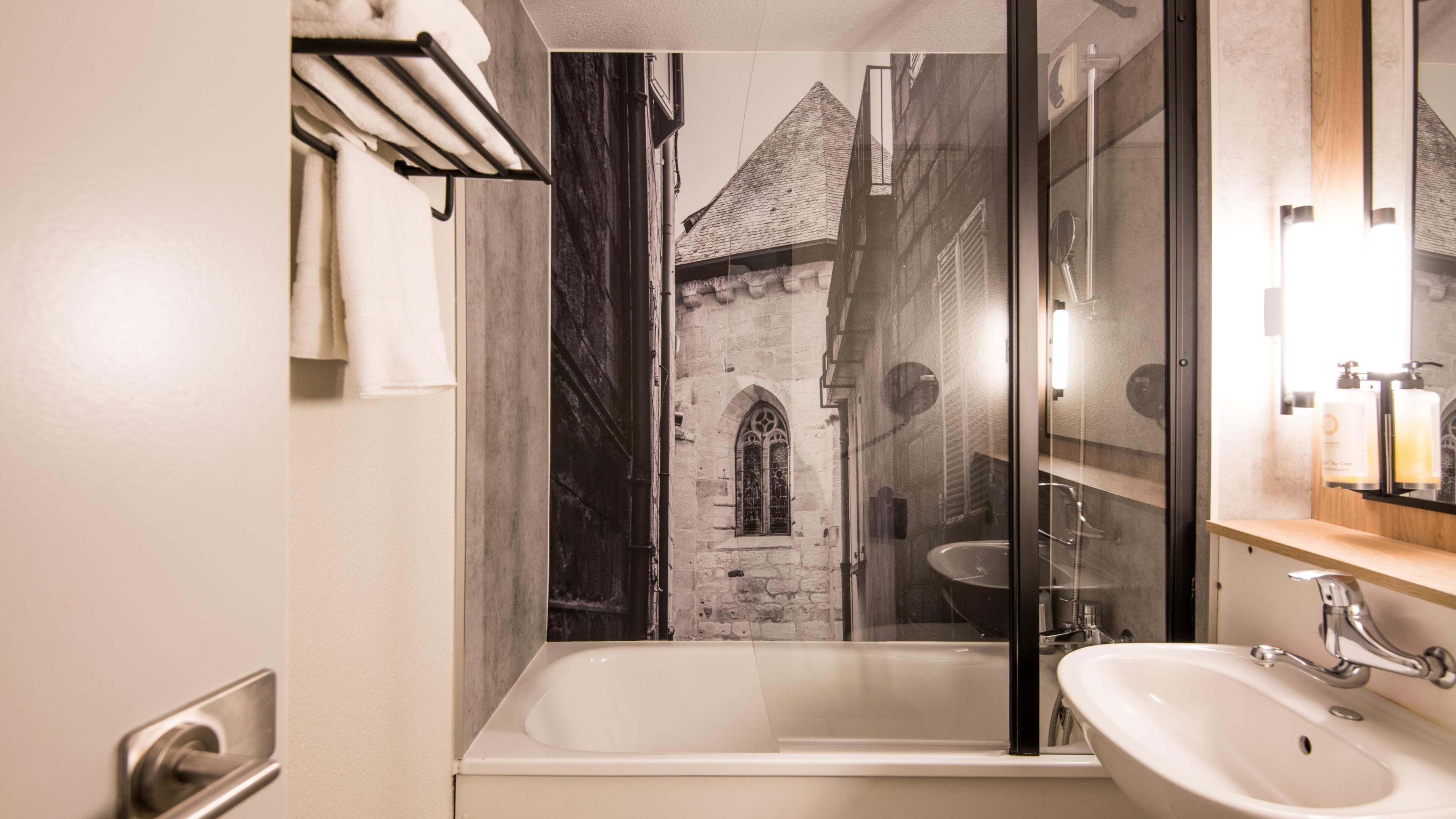 A bathroom with a bathtub, a sink, a mirror, and a towel rack.